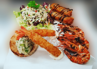 Assiette de gambas grillées, salade croquante et rondelles d’oignons frits, au Restaurant Taillecou Saint-Prex.