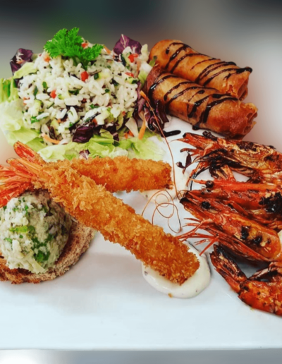 Assiette de gambas grillées, salade croquante et rondelles d’oignons frits, au Restaurant Taillecou Saint-Prex.